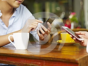 Hands of man and woman using cellphones