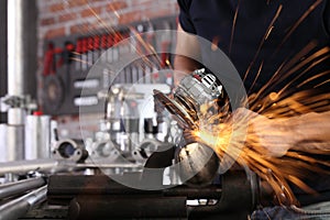 Hands man work in home workshop garage with angle grinder, sanding metal makes sparks closeup, diy and craft concept