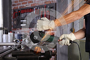 Hands man work in home workshop garage cut metal pipe, with construction gloves, cutting metal makes sparks closeup, diy and craft