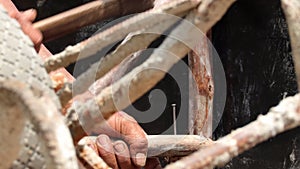 Hands of man working in construction site nailing in the wood with a hammer.