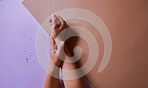 hands with a manicure on a sandy and pink background. in the background of a little glitterer