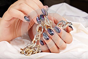 Hands with manicured nails with cat eye design holding a necklace