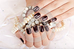 Hands with manicured nails colored with dark purple nail polish