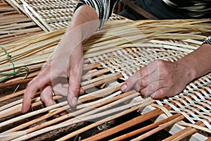 Hands manually mastering wicker fabric