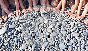 The hands of many children form a semicircle on the beach.