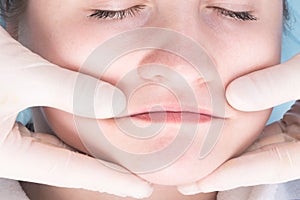 Hands of a massage therapist working on the neck and face area, top view, close-up