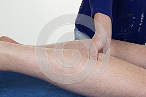 Hands massaging human calf muscle. Female therapist applying pressure on male leg.