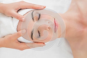 Hands massaging woman's forehead at beauty spa