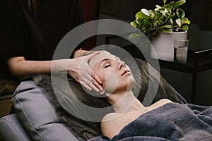 Hands massaging young woman`s head while she`s lying on a leather pillow photo
