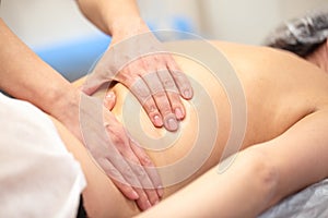 Hands of the masseur on the back of a young woman