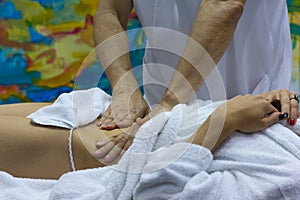 Hands of the masseur and the client`s body during massage treatm