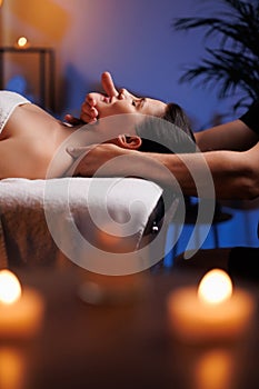 The hands of a masseuse make a manual massage of the head of a beautiful female client. The concept of scalp treatment