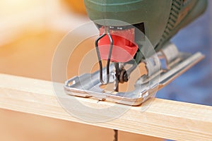 The hands of a master carpenter with an electric jigsaw in his hands cutting off a piece of wood. Male hands using fret