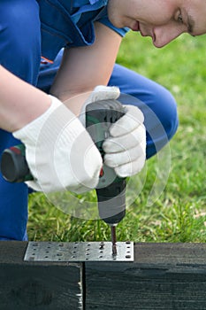 Hands of the master twist the screw into the foundation with a screwdriver