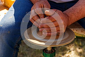 Hands of mature man making pottery on pottery wheel. Close-up