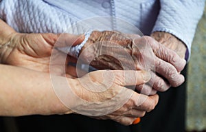 Hands of a mature wife or guardian holding the hands of her elderly woman or patient, as an expression of care and support.Close u