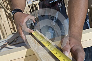 Hands Measuring Wooden Beam