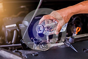Hands of mechanic check water in car radiator and add water to car radiator, service and maintenance of cars or vehicles,
