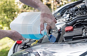 Hands of mechanic pouring washer in a car