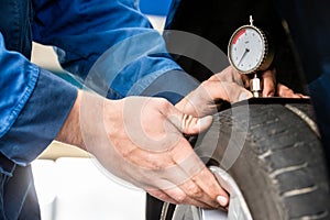 Hands Of Mechanic Pressing Gauge Into Tire In Garage