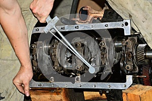 Hands of mechanic stretch cap main bearings of an internal combustion engine with a torque wrench. photo