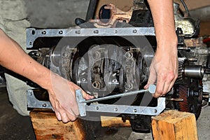 Hands of mechanic stretch crankshaft bearing cap of an internal combustion engine with a torque wrench.