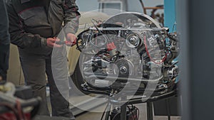 Hands of a mechanic are visible adjusting or setting idle or air mixture screws on a vintage freshly rebuilt air cooled engine.