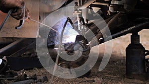 Hands of mechanic welding for repair the truck wishbone control arm of front wheel