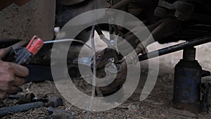 Hands of mechanic welding for repair the truck wishbone control arm of front wheel