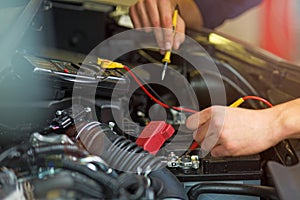 Auto mechanic checking car battery voltage