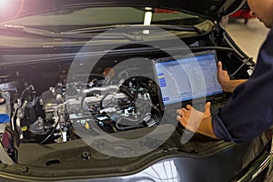 Mechanic Using Laptop While Examining Car Engine