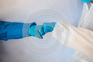 Hands in medical gloves greeting each other with fist bump on white background