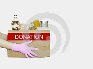 Hands in medical gloves hold a box of food for the poor. Isolated on a white background. The concept of donations