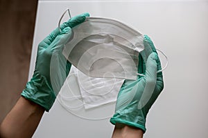 Hands in medical gloves hold a mask against coronovirus
