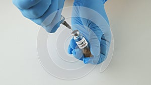 Hands with medical gloves holding a syringe and a vial of vaccine for nCoV.