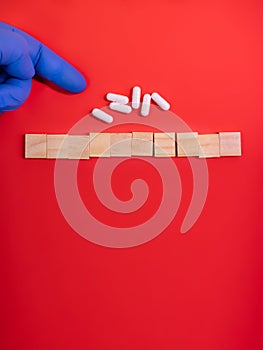 Hands in medical gloves point on wooden blocks on colored red background with medicine pills. Concept book cover medical