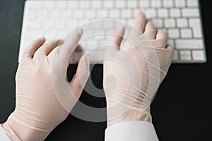 Hands in medical protection gloves typing on laptop keyboard, virus epidemy concept