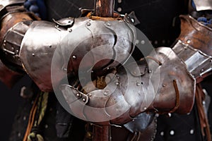 Hands of a medieval knight in iron protective gauntlets holding a spear Part of the military uniform