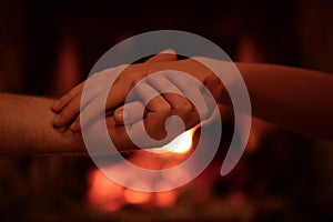 The hands of men and women against the backdrop of fire