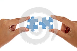 Hands merging two jigsaw puzzle pieces against white photo