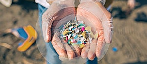 Hands with microplastics on the beach