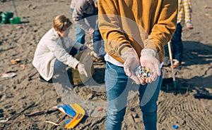 Hands with microplastics on the beach