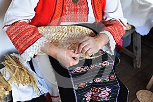 Hands of middle-aged woman osier-knitter craftswoman in Bulgarian folk costume