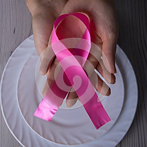 Hands of a middle-aged woman sitting at a table with cutlery and a ribbon - a symbol of health, a concept on the topic of proper n