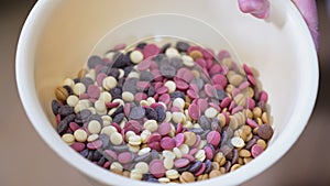 Hands mixing ruby white and dark chocolate callets in bowl confectionary concept