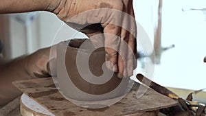 Hands modeling a bowl of red clay