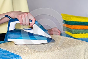 Hands with a modern iron with a steam ironing system for a clean, wrinkled towel. Homework concept, housewife