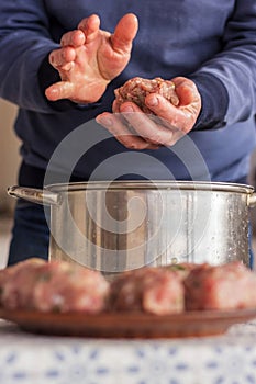Hands molding meatball cutlets. A man deftly sculpts cutlets from minced meat