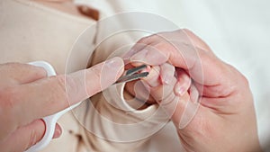 Hands of mom cutting tiny baby nails with children scissors