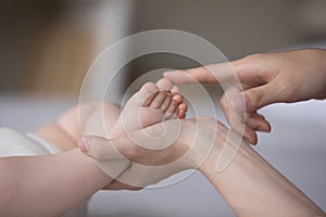 Hands of mom touching little baby tiny feet, caressing kid